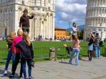 Tourists having fun holding up the leaning tower of Pisa